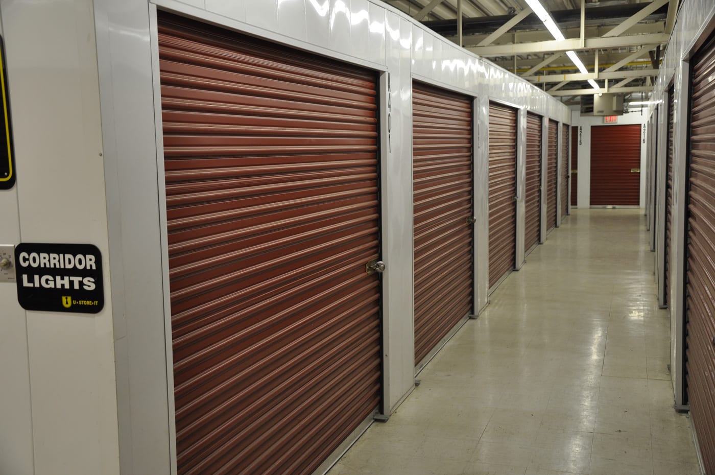 Well-lit interior hallway of U•STORE•IT's Edmonton North facility displays clean, organized storage units with secure roll-up doors, numbered units, and wide corridors for easy access to climate-controlled storage solutions.